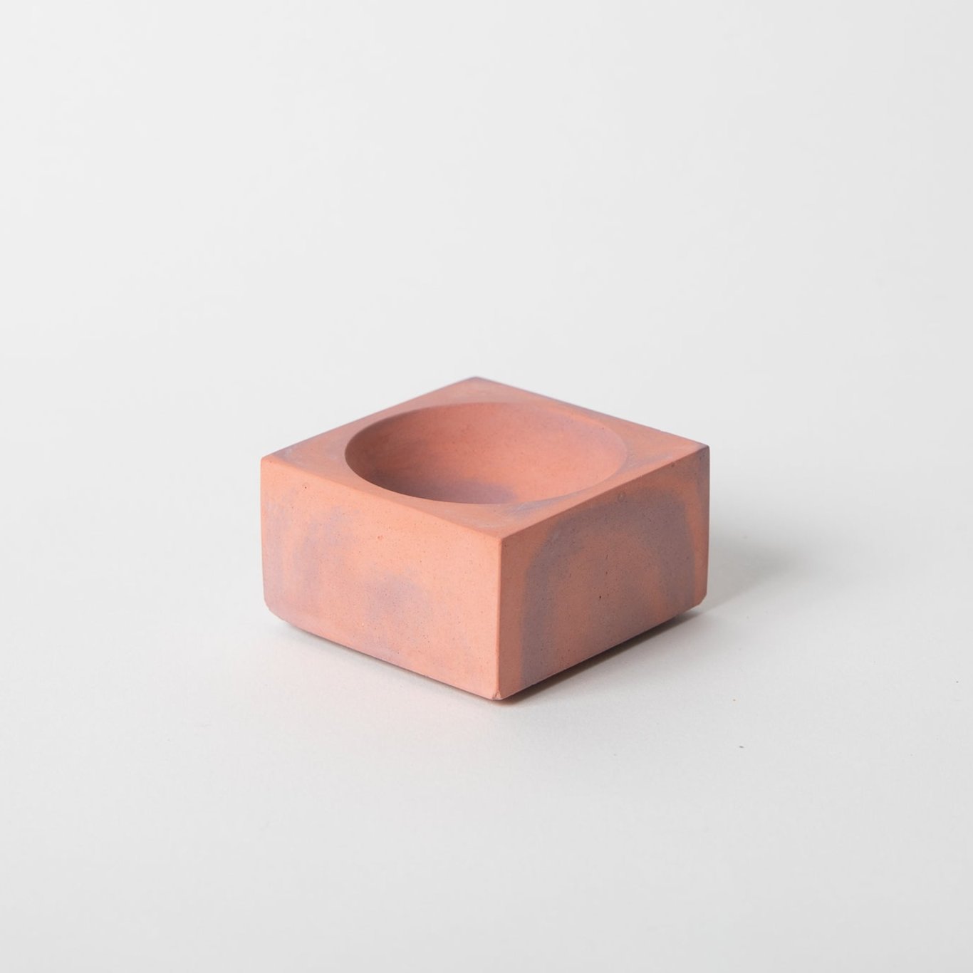 Square concrete incense holder in coral and mauve.