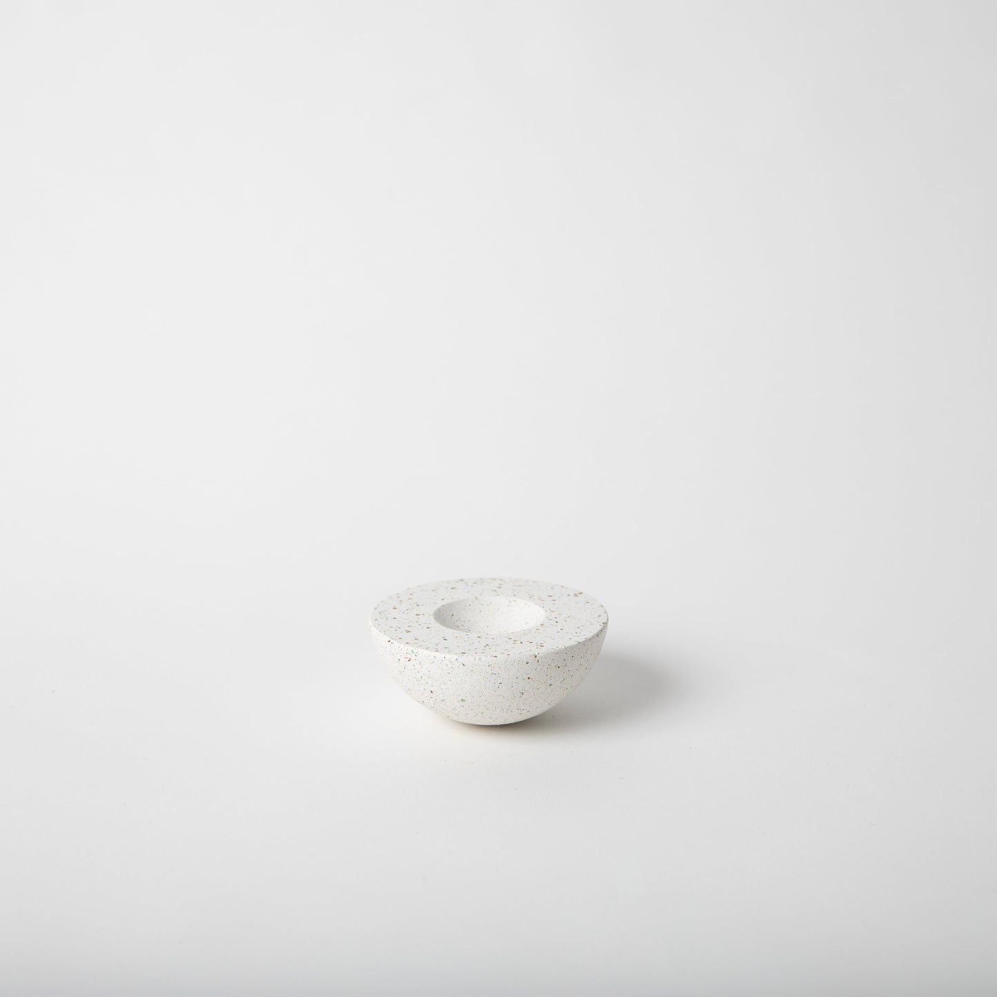 Half sphere shaped incense holder in white terrazzo.